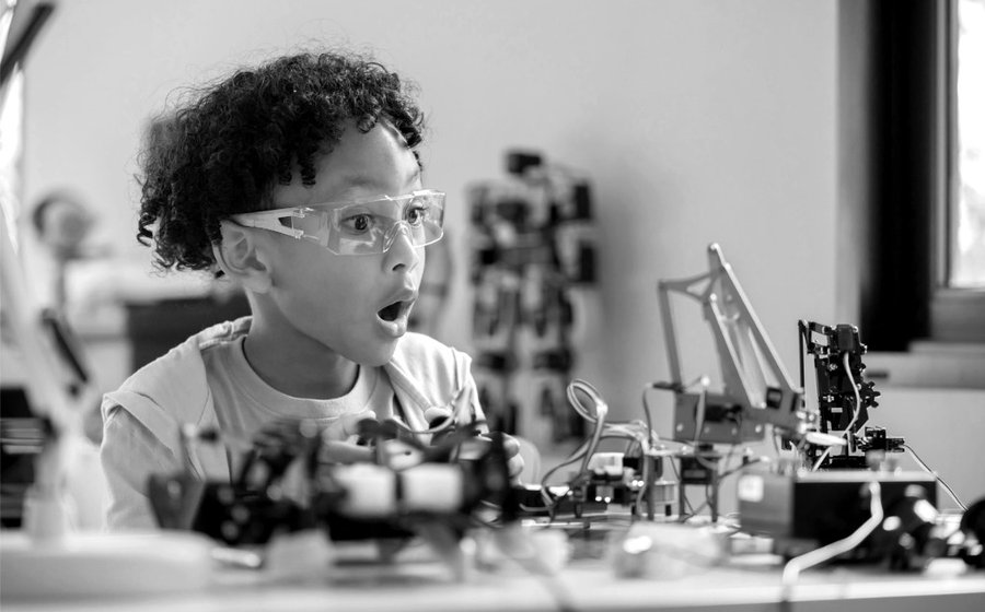 A child excitedly experiments with robot assembly and uses coding to give commands.